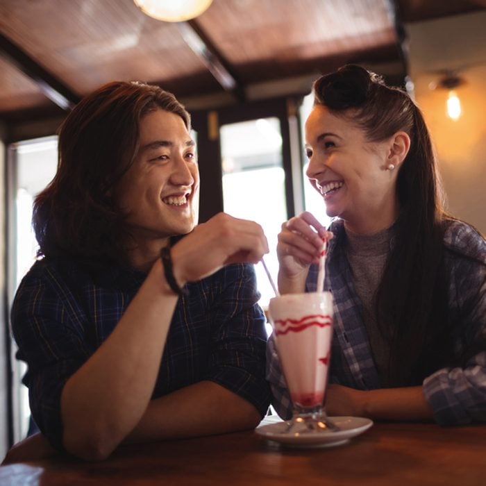 Happy couple having milkshake in restaurant
