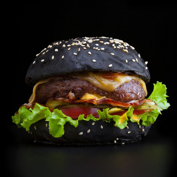 Tasty and appetizing hamburger isolated black with a black bun and bacon.