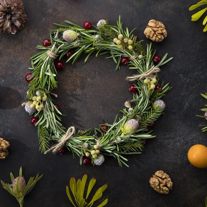 Christmas wreath of rosemary on a beautiful brown background, with berries, cones, currants, twigs and leaves around.