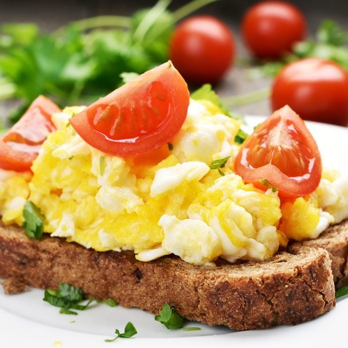 Breakfast scrambled eggs and tomato slices on bread