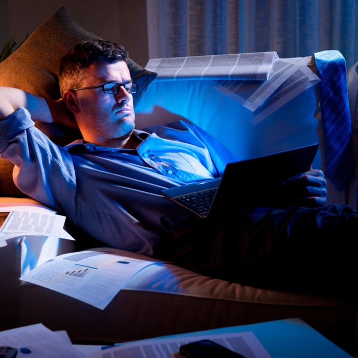 Man sitting on a dark, cluttered couch