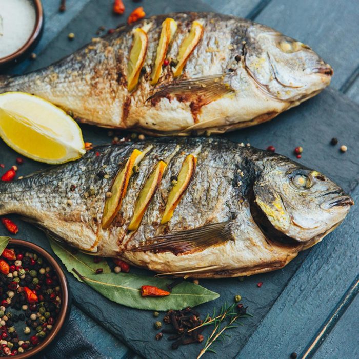 Delicious grilled sea bream fish with rosemary, lemon and peppercorns on wooden background. Culinary healthy cooking.; Shutterstock ID 577296571; Job (TFH, TOH, RD, BNB, CWM, CM): TOH