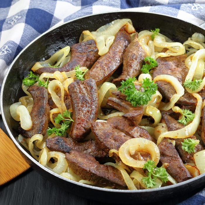 close-up of delicious veal liver pieces stir fried and stewed with onion rings in a skillet