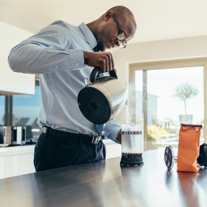 Man pouring hot water in coffee maker.