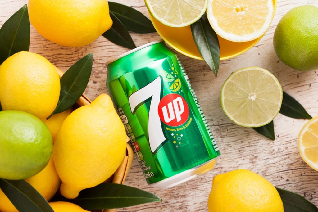 Aluminium can of 7UP lemonade soda drink with fresh lemons and limes.