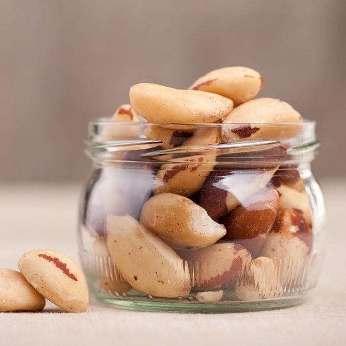 Brazil nuts from Bertholletia excelsa tree in glass jar and two nuts out of jar