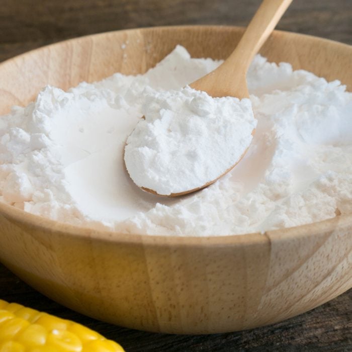 Corn flour in spoon on wooden.