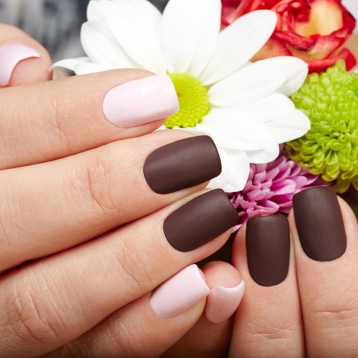 Hands with pink and purple manicured nails holding a bouquet of flowers