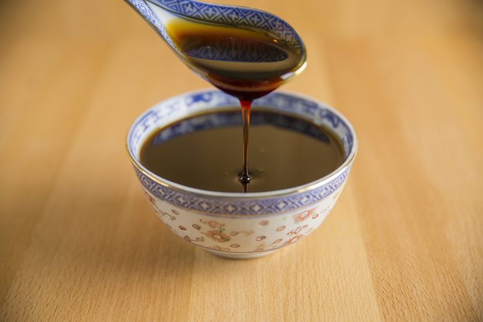 Pomegranate molasses flowing from the spoon on wooden background.
