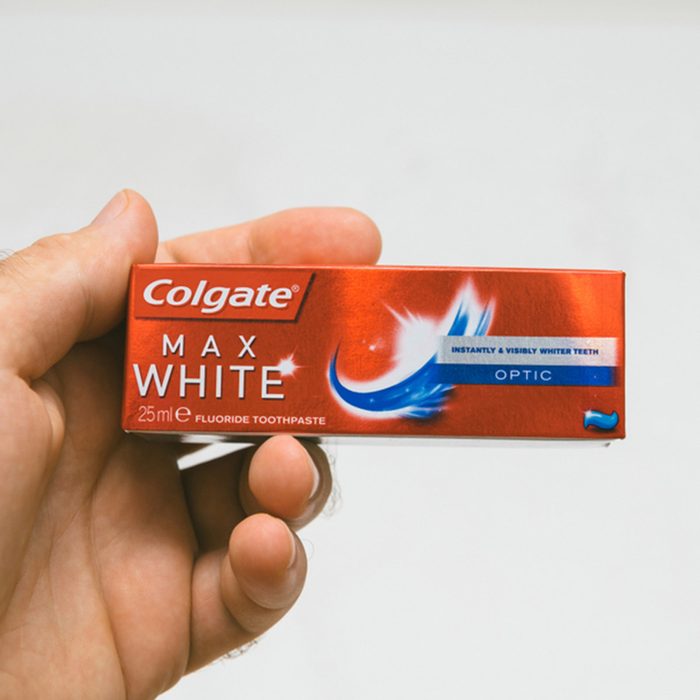 Man holding Colgate small air security rules conformed travel toothpaste against white background