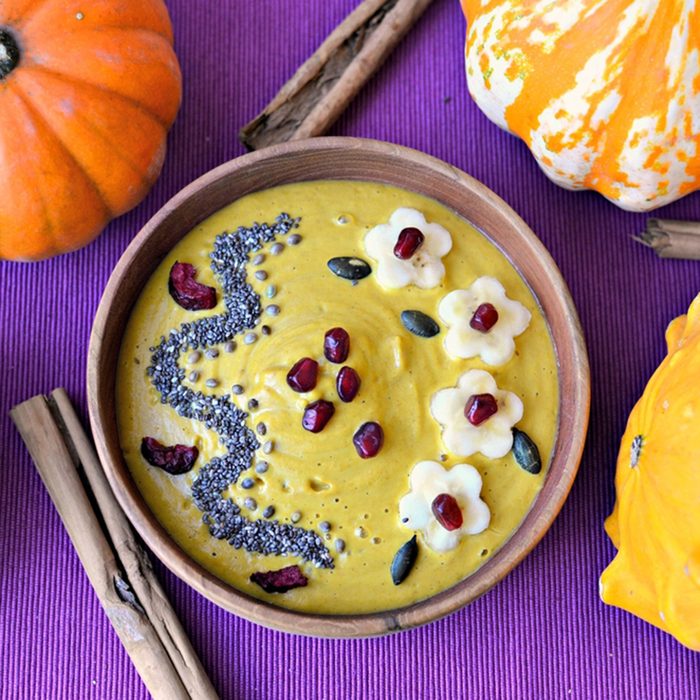 Butternut squash and turmeric smoothie bowl topped with banana, pomegranate, pumpkin kernels, chia, hemp seeds and dried cherries.