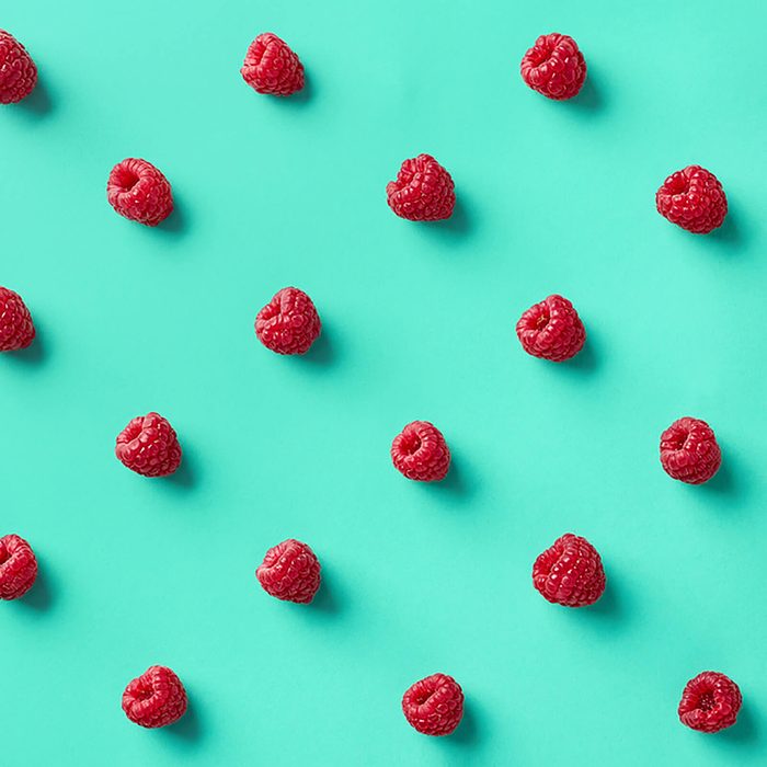 Colorful pattern of raspberries on blue background.