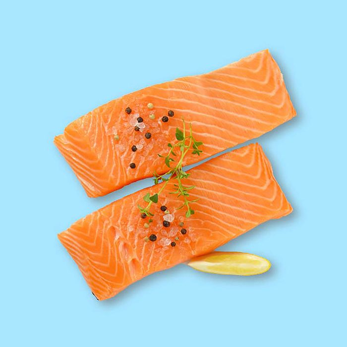 two raw salmon fillets with spice on white background