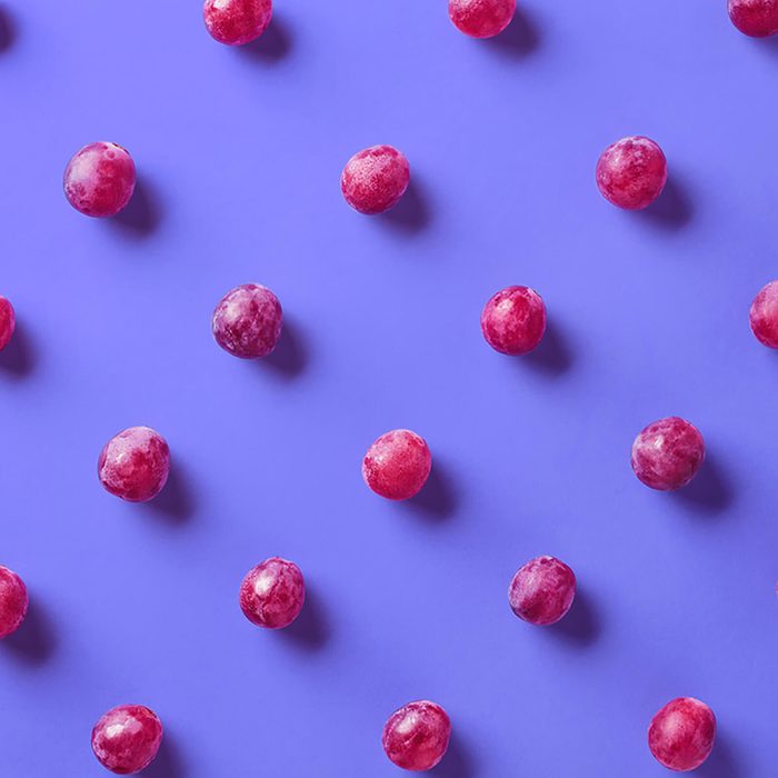 Colorful pattern of grapes on purple background.