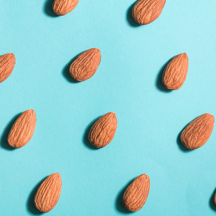 Symmetrical pattern of almonds on blue. Flat lay.