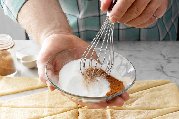 mixing cinnamon and sugar in a small glass bowl with a whisk