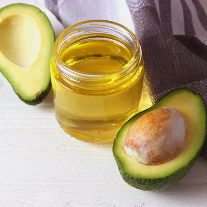 avocado oil and avocado fruit on a wooden table.