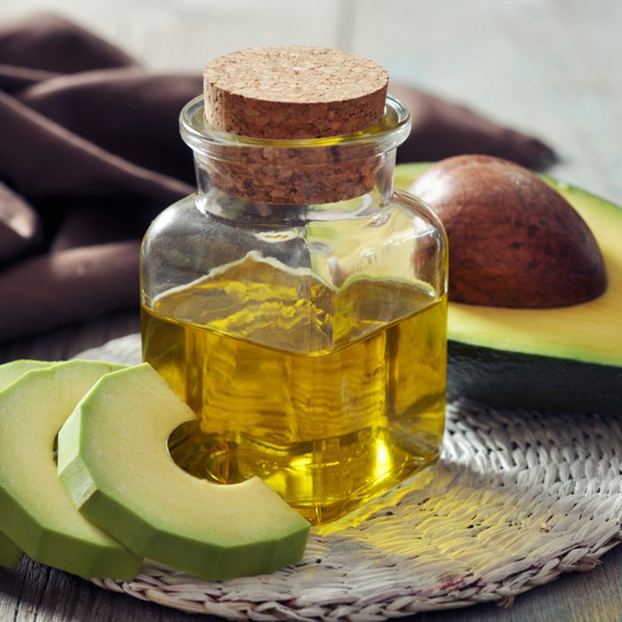 bottle of avocado essential oil with fresh avocado fruit closeup