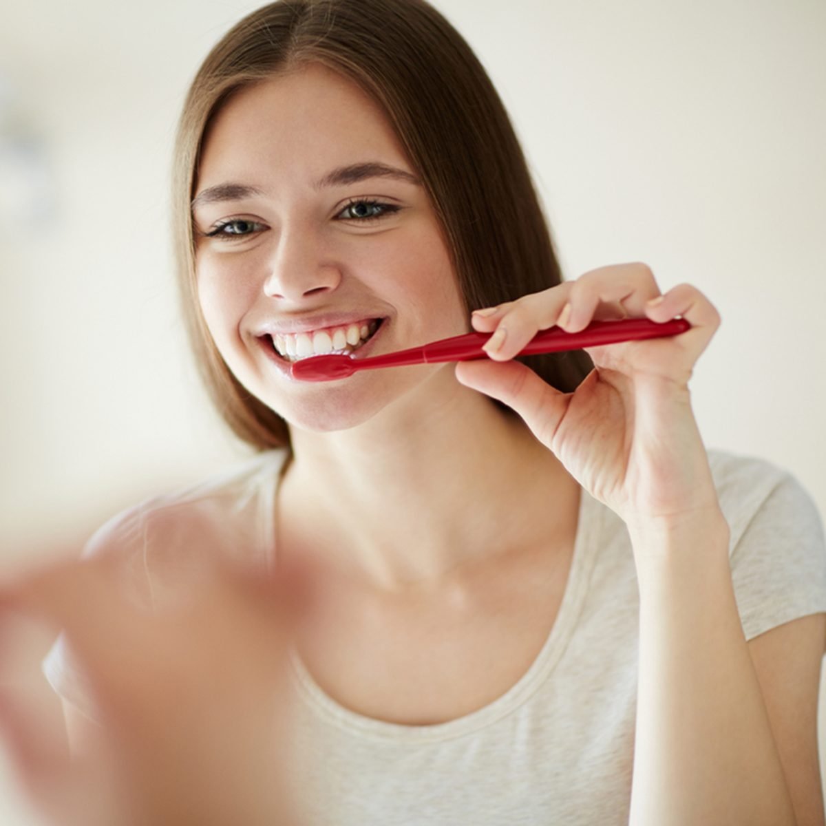 Young woman brushing her teeth at mirror