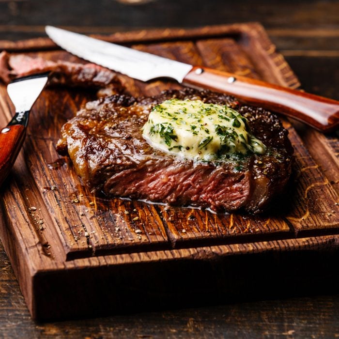 Grilled Medium rare steak Ribeye with herb butter on cutting board serving size
