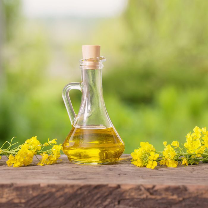 rapeseed oil (canola) and rape flowers on wooden table