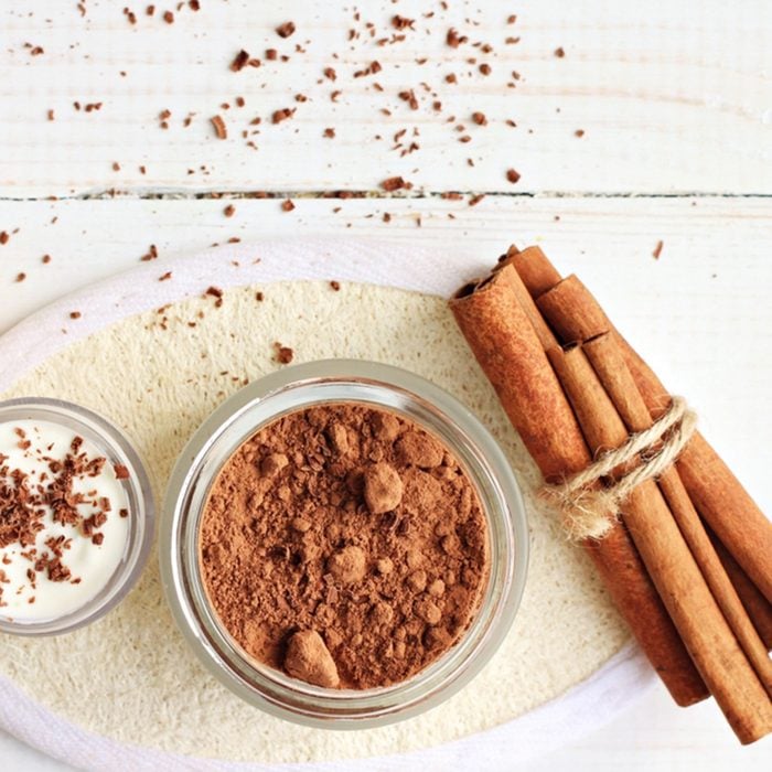 Chocolate skin treatment. Cosmetic jar with cocoa, cinnamon sticks, chocolate body butter.