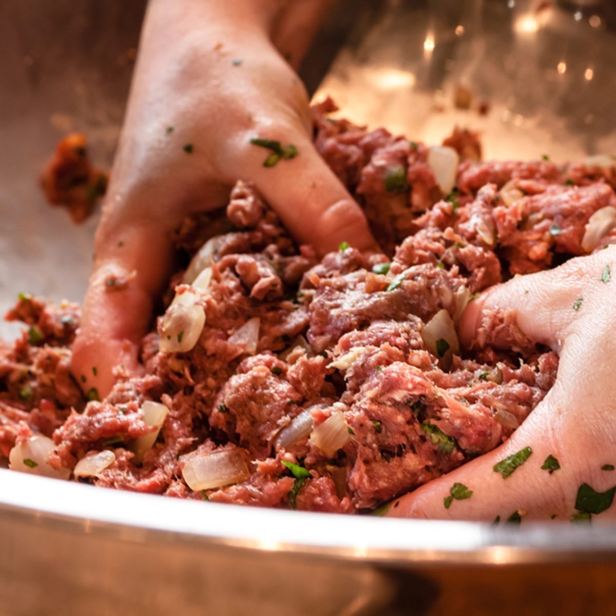 Pair of hand mixing raw ground beef mixture preparing to make fresh gourmet hamburgers