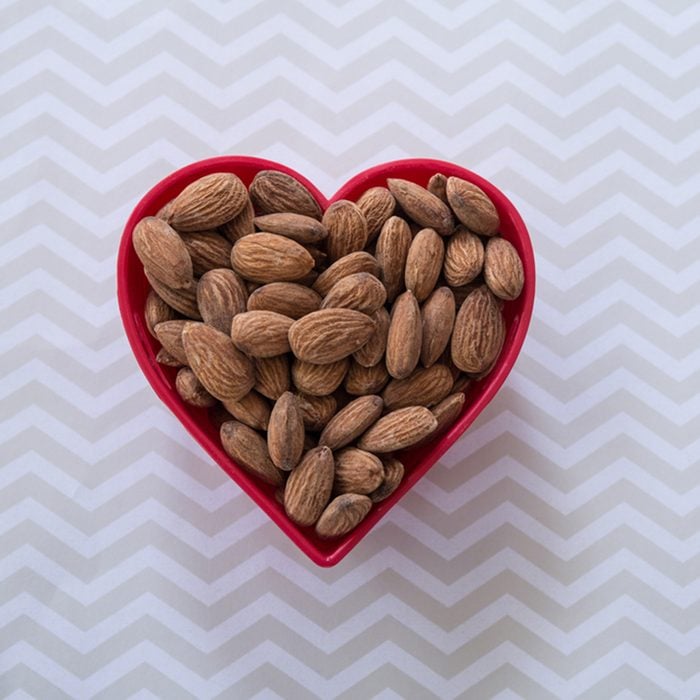 Snack of almonds in red heart shaped bowl on chevron patterned background