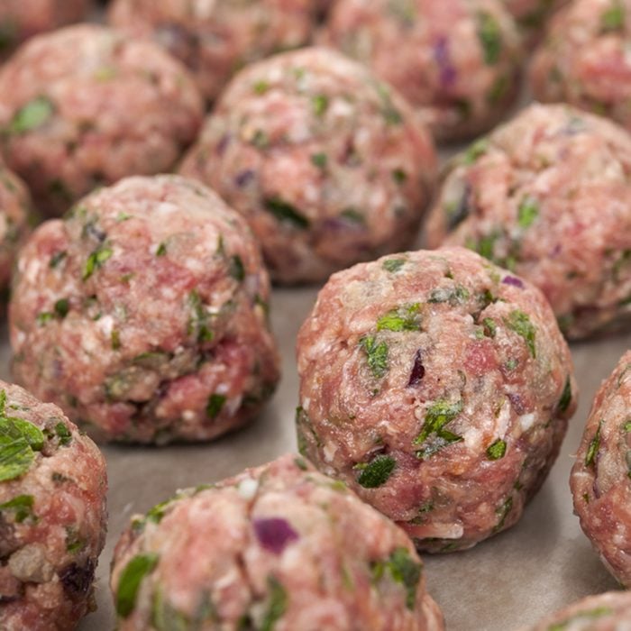 Rows of raw homemade meatballs prepared for cooking on a tray