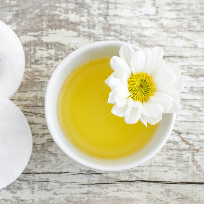 Small white bowl with olive oil and cotton pad for natural skin care