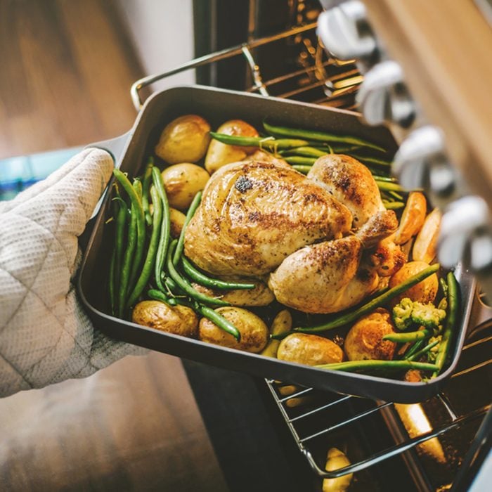 Cook taking ready fried baked chicken with vegetables from the oven. Home cooking concept. ; Shutterstock ID 1175873314; Job (TFH, TOH, RD, BNB, CWM, CM): TOH