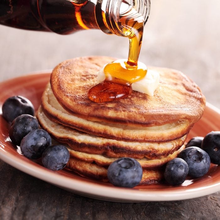 Close-up of pouring maple syrup on stack of pancakes