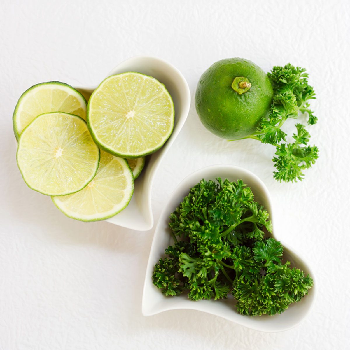 Sliced lime and celery in heart shaped plates over white paper. Green healthy drink ingredients. Fruits and vegetables background. Text space; Shutterstock ID 409140517; Job (TFH, TOH, RD, BNB, CWM, CM): Taste of Home