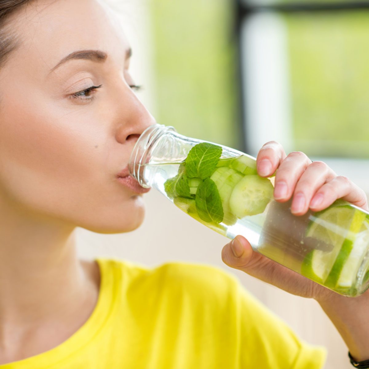 Close-up of a woman drinking water with mint, cucumber and lime during a workout with dumbbells. Detox dieting concept; Shutterstock ID 622941011; Job (TFH, TOH, RD, BNB, CWM, CM): Taste of Home