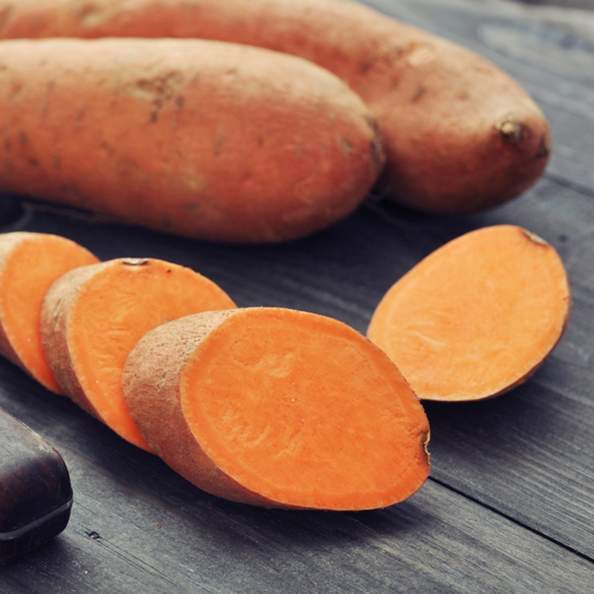 Raw sweet potatoes on wooden background