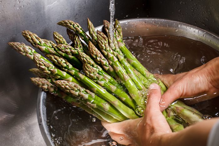 Man's hands washing asparagus.