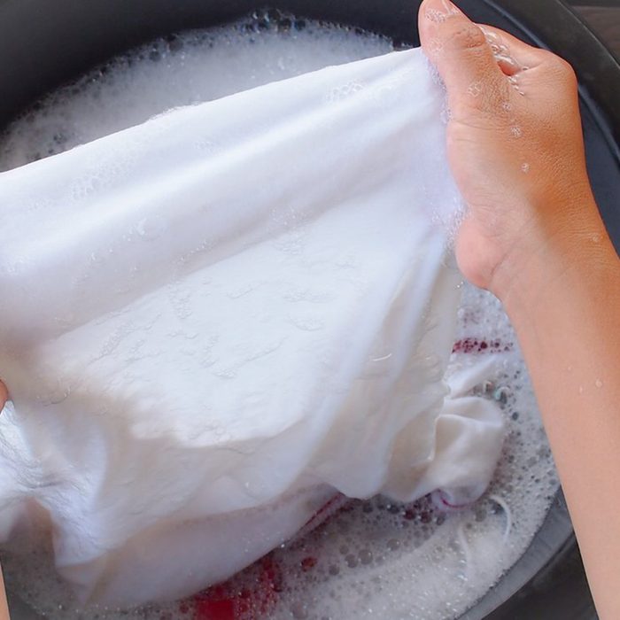 Washing cloth in a bucket of soapy water