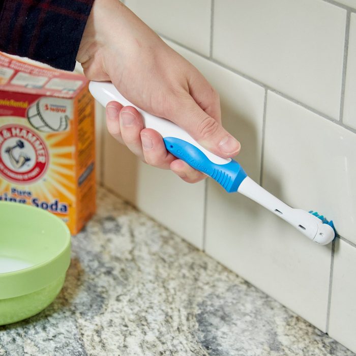 Using a toothbrush to clean grout