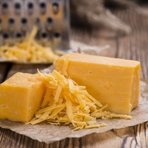 Cheddar Cheese (grated) as close-up shot on an old vintage wooden table