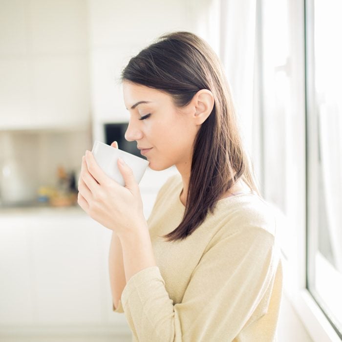 Modern working woman lifestyle-drinking coffee or tea in the morning in the kitchen,starting your day.