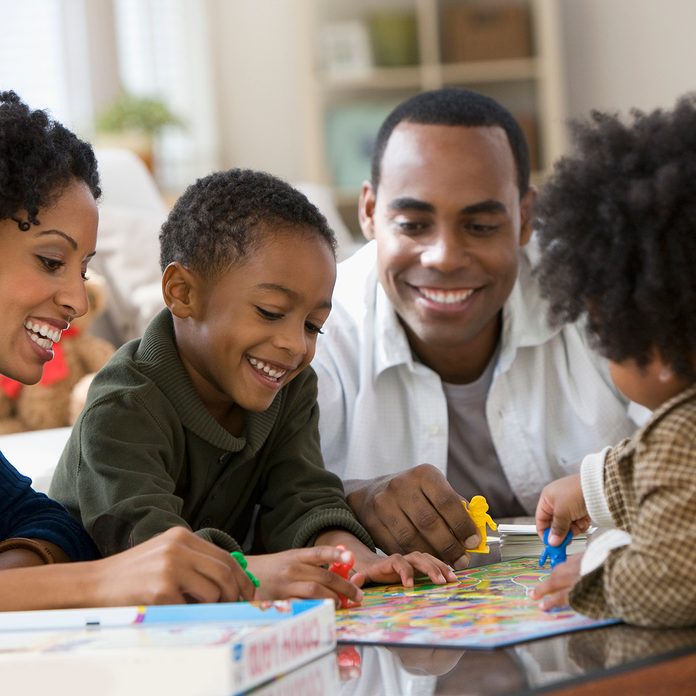African American family playing board game together