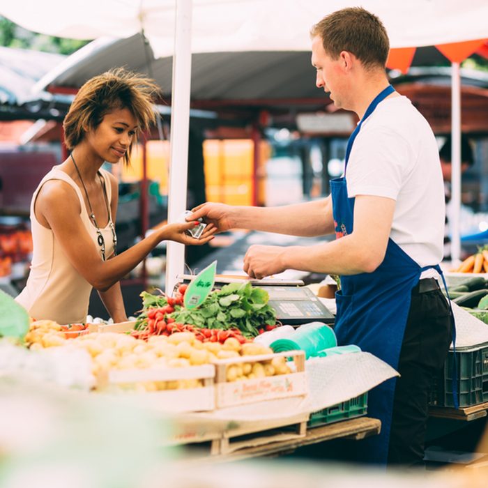 Young black woman paying for vegetables at farmer's market