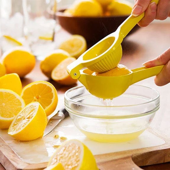 person using a squeezer to empty the juice from a lemon and into a bowl