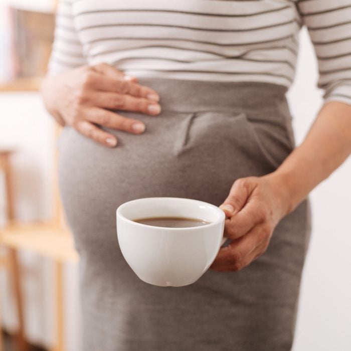 Pleasant pregnant woman holding a cup of coffee