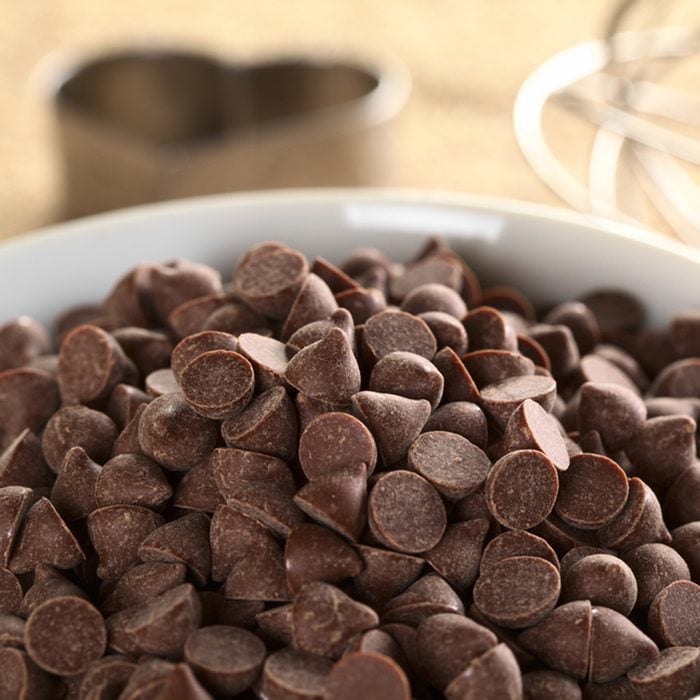 Chocolate chips surrounded by baking utensils (beater and cutters) (Selective Focus, Focus on the chocolate chips on top and the ones in the same plane); Shutterstock ID 101336626; Job (TFH, TOH, RD, BNB, CWM, CM): TOH