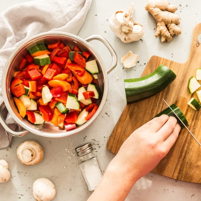 Cooking - chef's hands preparing vegetable vegetarian stew (thick soup). Kitchen scenery - pot with recipe ingredients around on the grey stone worktop captured from above (top view, flat lay). ; Shutterstock ID 1034866882; Job (TFH, TOH, RD, BNB, CWM, CM): TOH