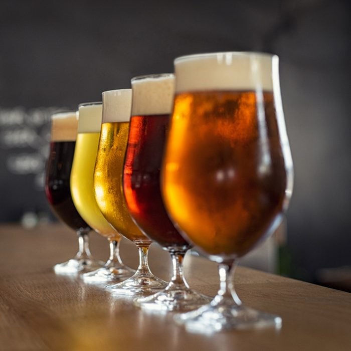 Glasses with different sorts of craft beer on wooden bar.