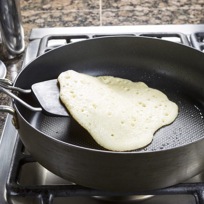 Photo of focus on pancake batter being fried into a pancake within hot frying pan