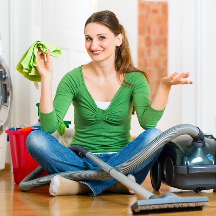 Young woman cleaning at home, she has a cleaning day and using a vacuum cleaner cleaning products and a bucket