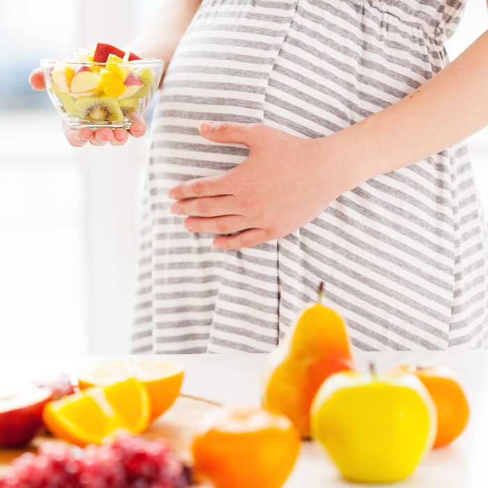 pregnant woman holding a plate with fruit salad